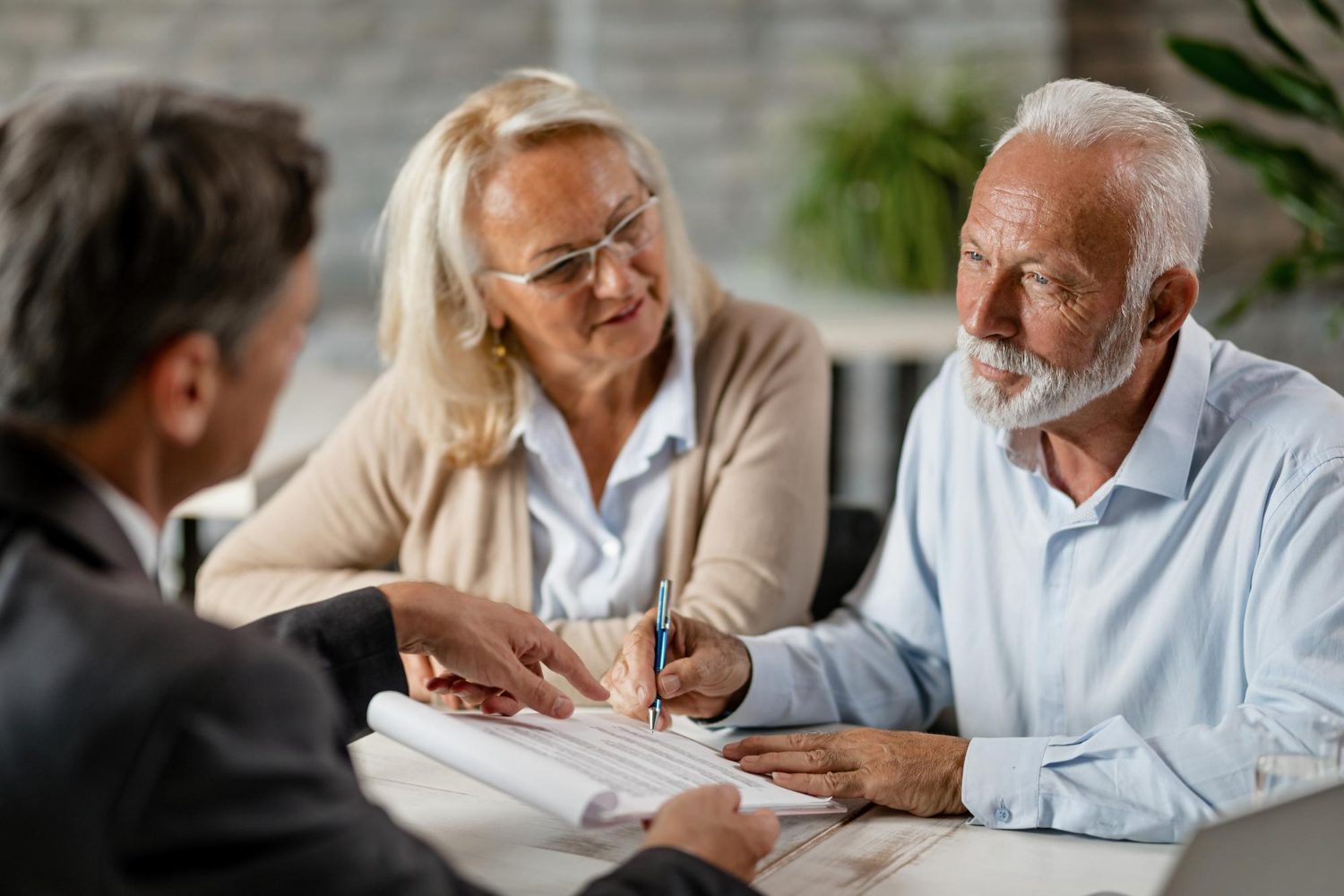 mature couple having a meeting with bank manager and signing lease agreement in the office